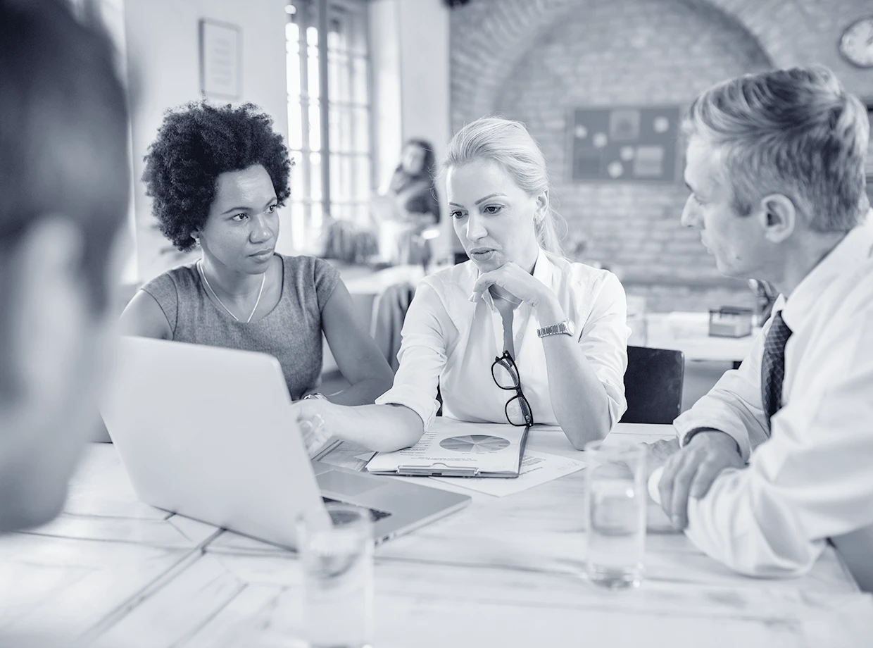 mid-adult-businesswoman-talking-her-colleagues-while-using-laptop-pointing-screen-office