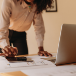 Female SME owner reviewing cash flow forecasts and outstanding invoices to plan her finances.
