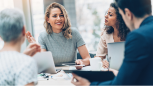 A diverse group of four professionals in a meeting discussing business in a modern office.