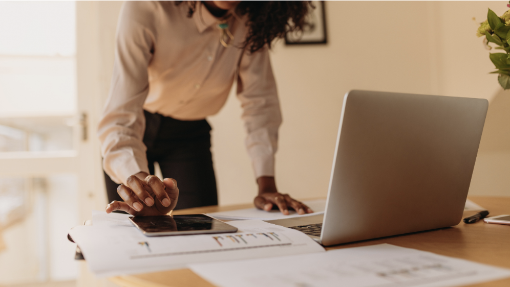 Female SME owner reviewing cash flow forecasts and outstanding invoices to plan her finances.